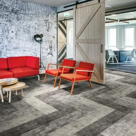 Modern breakout area with grey flooring and red chairs