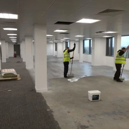 Two contractors in high vis jackets preparing a subfloor