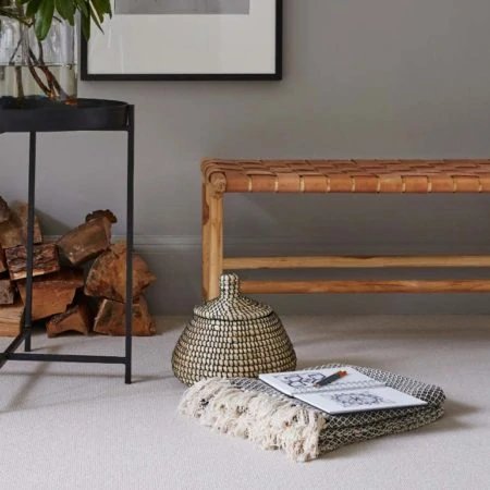 Hallway setting with table of flowers and stool, rug and books on the floor