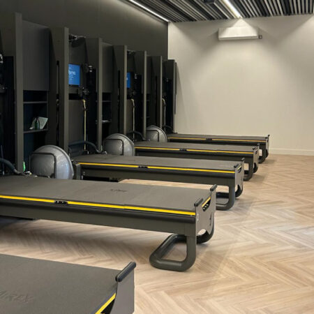 Row of reformer machines installed over light herringbone LVT flooring